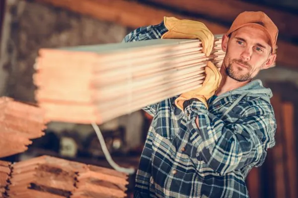 deck builder carrying wooden deck boards for deck design and installation